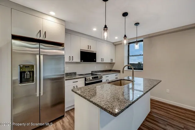 a kitchen with stainless steel appliances granite countertop a sink a refrigerator and a granite counter tops