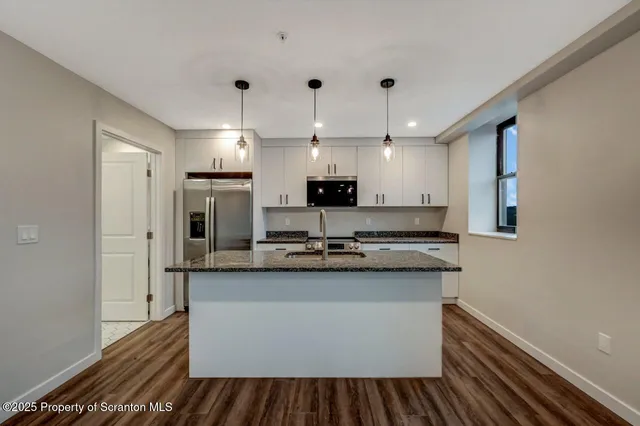 a kitchen with kitchen island a sink stainless steel appliances and cabinets