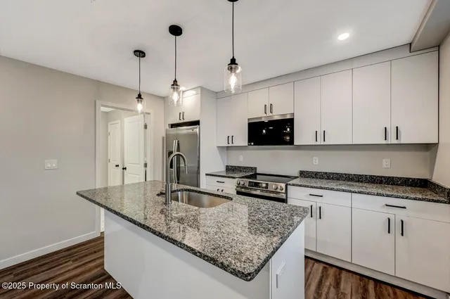 a kitchen with granite countertop a sink a counter top space and stainless steel appliances