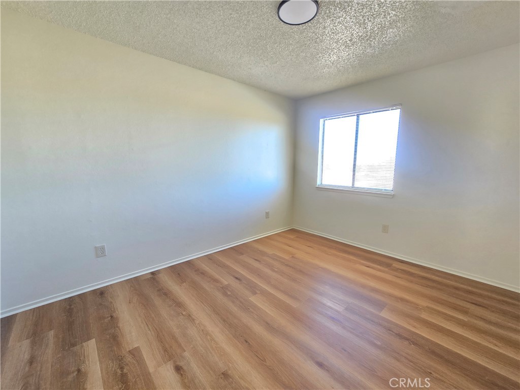 8318 Dogbane Avenue, Unit A California City, CA 93505 - Photo 11 of 12 an empty room with wooden floor and windows