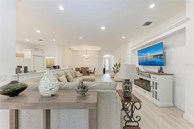 a living room with furniture a flat screen tv and kitchen view