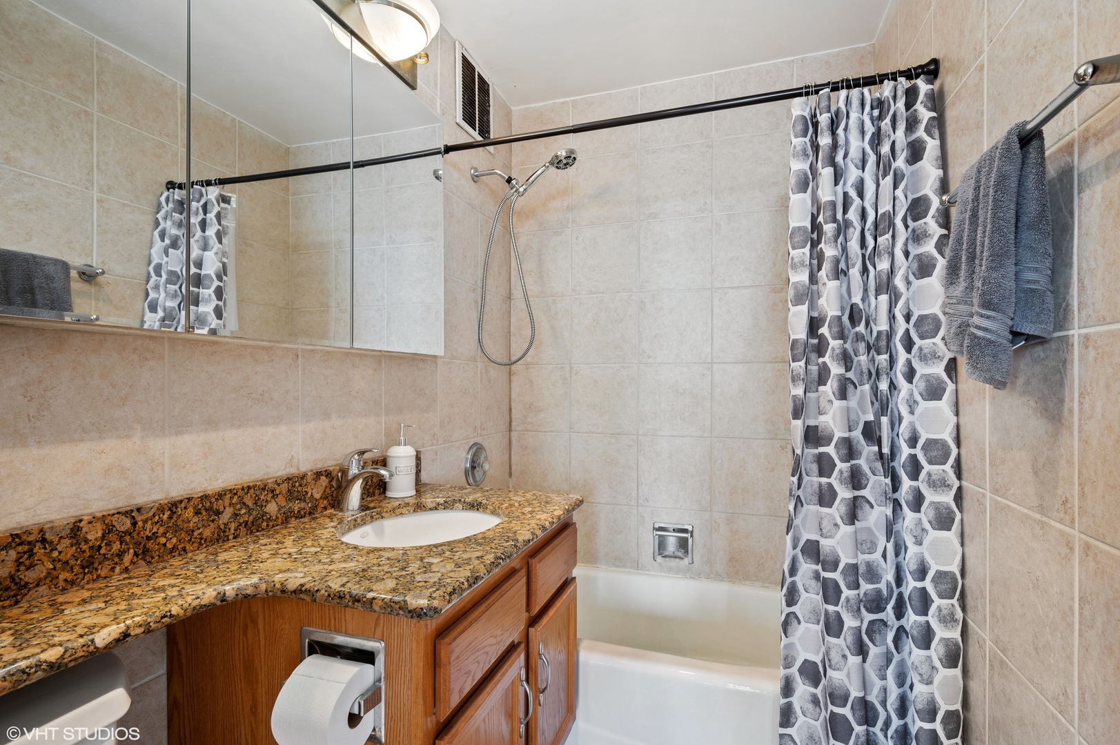 655 West Irving Park Road, Unit 4005 Chicago, IL 60613 - Photo 9 of 12 a bathroom with a granite countertop sink a mirror and shower