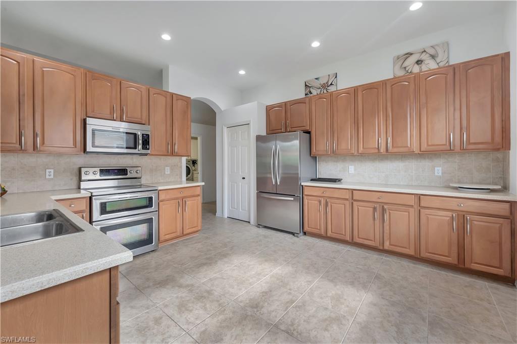 14095 Mirror Court Naples, FL 34114 - Photo 13 of 45 Kitchen with stainless steel appliances, tasteful backsplash, arched walkways, recessed lighting, and light tile patterned flooring