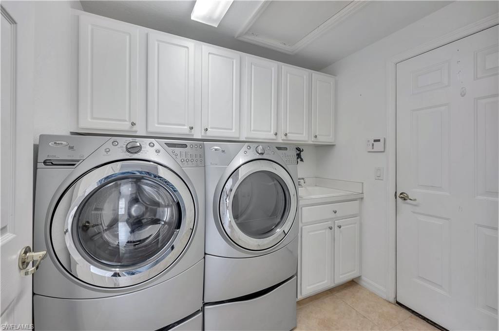 14095 Mirror Court Naples, FL 34114 - Photo 22 of 45 Laundry area with light tile patterned floors, washer and clothes dryer, and cabinet space