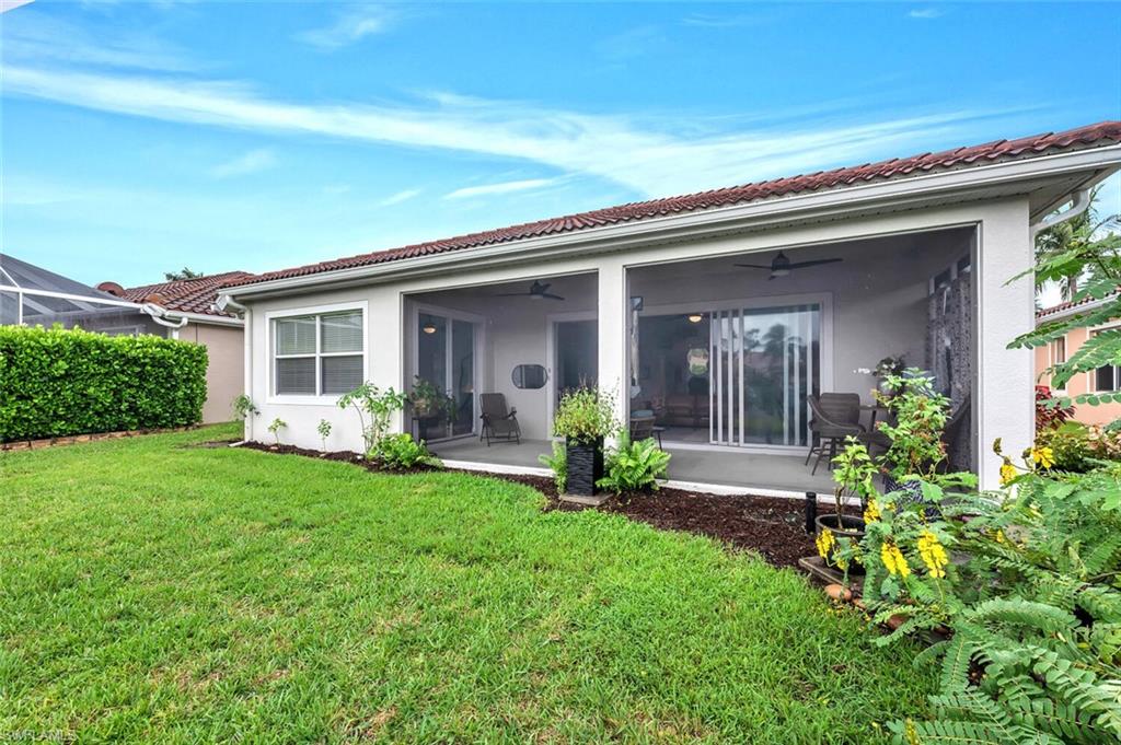 14095 Mirror Court Naples, FL 34114 - Photo 33 of 45 Back of house with a ceiling fan, stucco siding, a yard, a sunroom, and a tiled roof