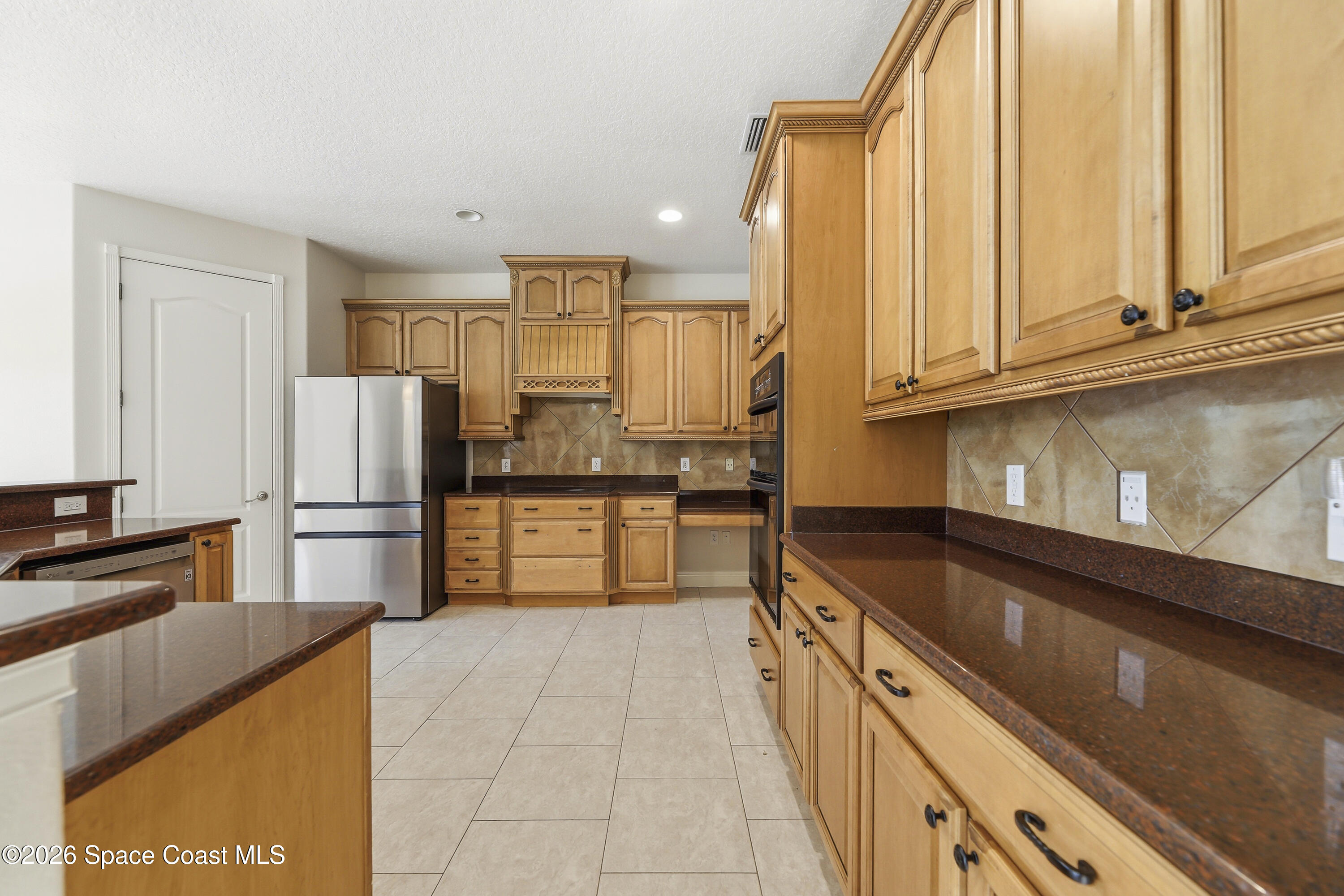 2300 Duncil Lane Malabar, FL 32950 - Photo 26 of 86 a kitchen with granite countertop a refrigerator and cabinets