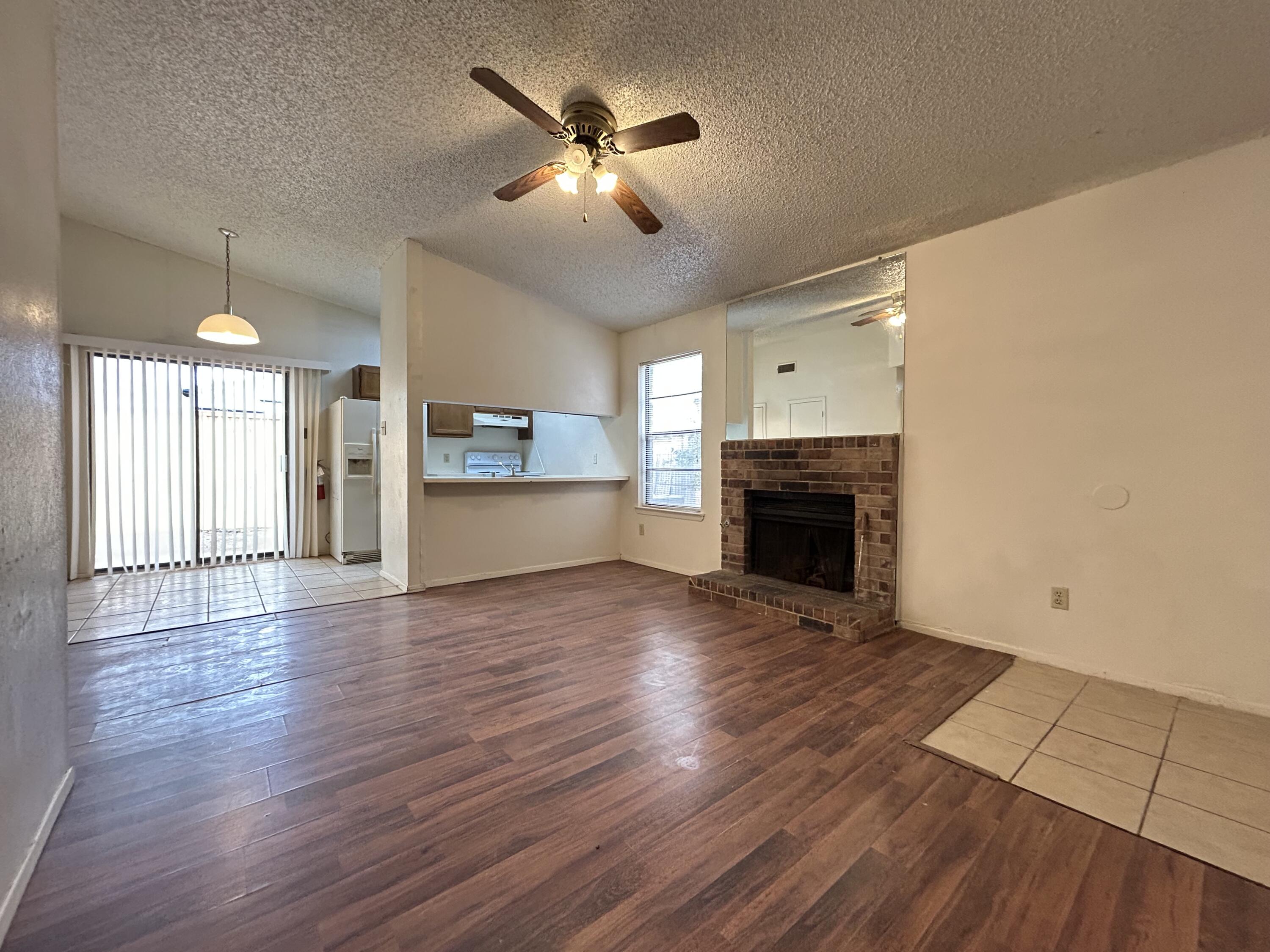 139 North Troy Avenue, Unit B Lubbock, TX 79416 - Photo 3 of 9 an empty room with wooden floor a fireplace a ceiling fan and windows