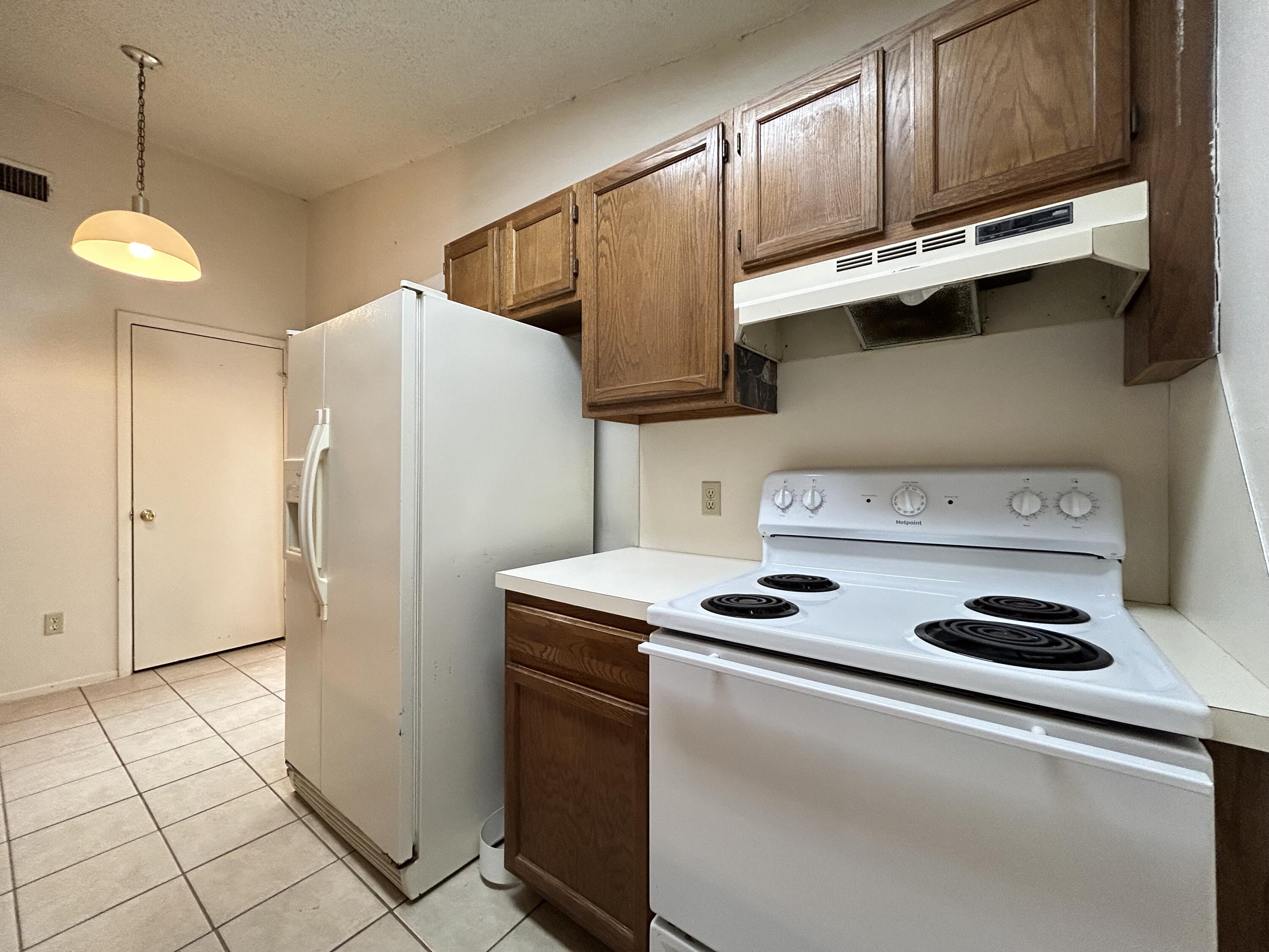 139 North Troy Avenue, Unit B Lubbock, TX 79416 - Photo 5 of 9 a kitchen with stainless steel appliances granite countertop a refrigerator a stove and a sink with wooden cabinets
