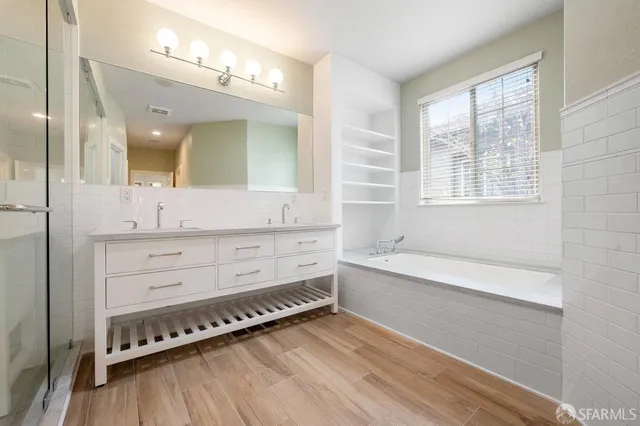 a bathroom with a bathtub a double vanity sink and mirror