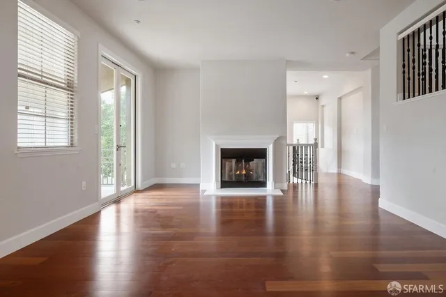an empty room with wooden floor and fireplace