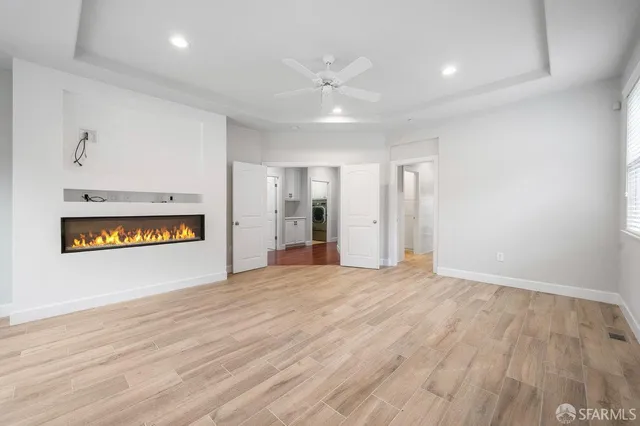 a view of an empty room with wooden floor kitchen and a window