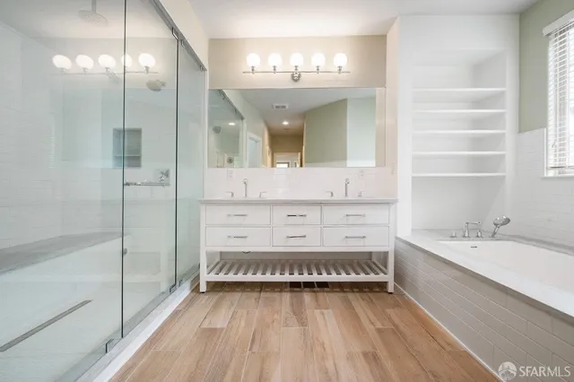 a bathroom with a double vanity sink mirror and bathtub