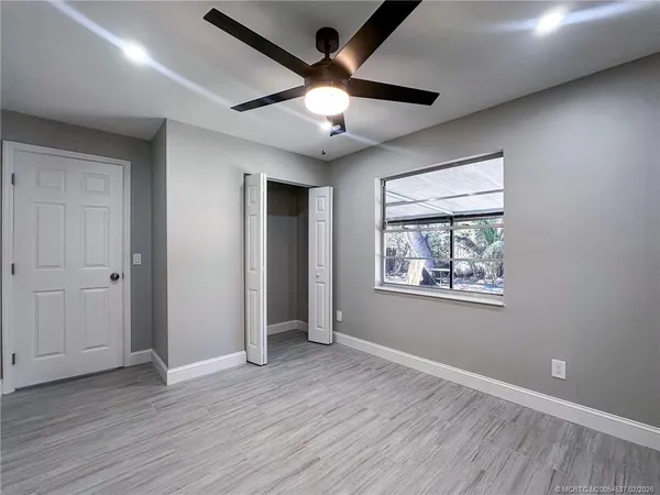 a view of an empty room with wooden floor and a ceiling fan