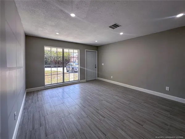 an empty room with wooden floor and windows