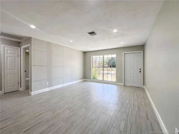 a view of an empty room with wooden floor and windows