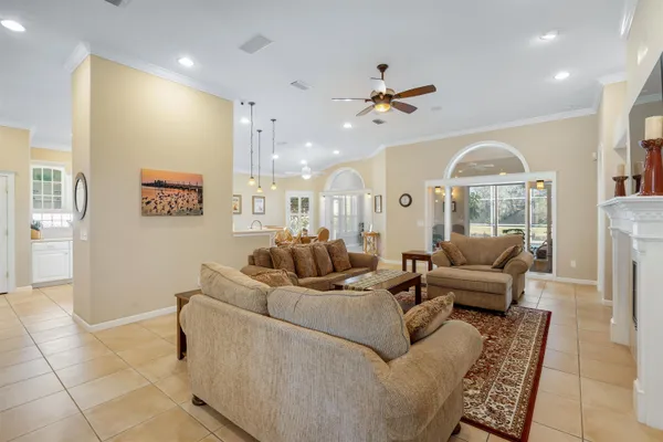 a living room with furniture kitchen view and a chandelier