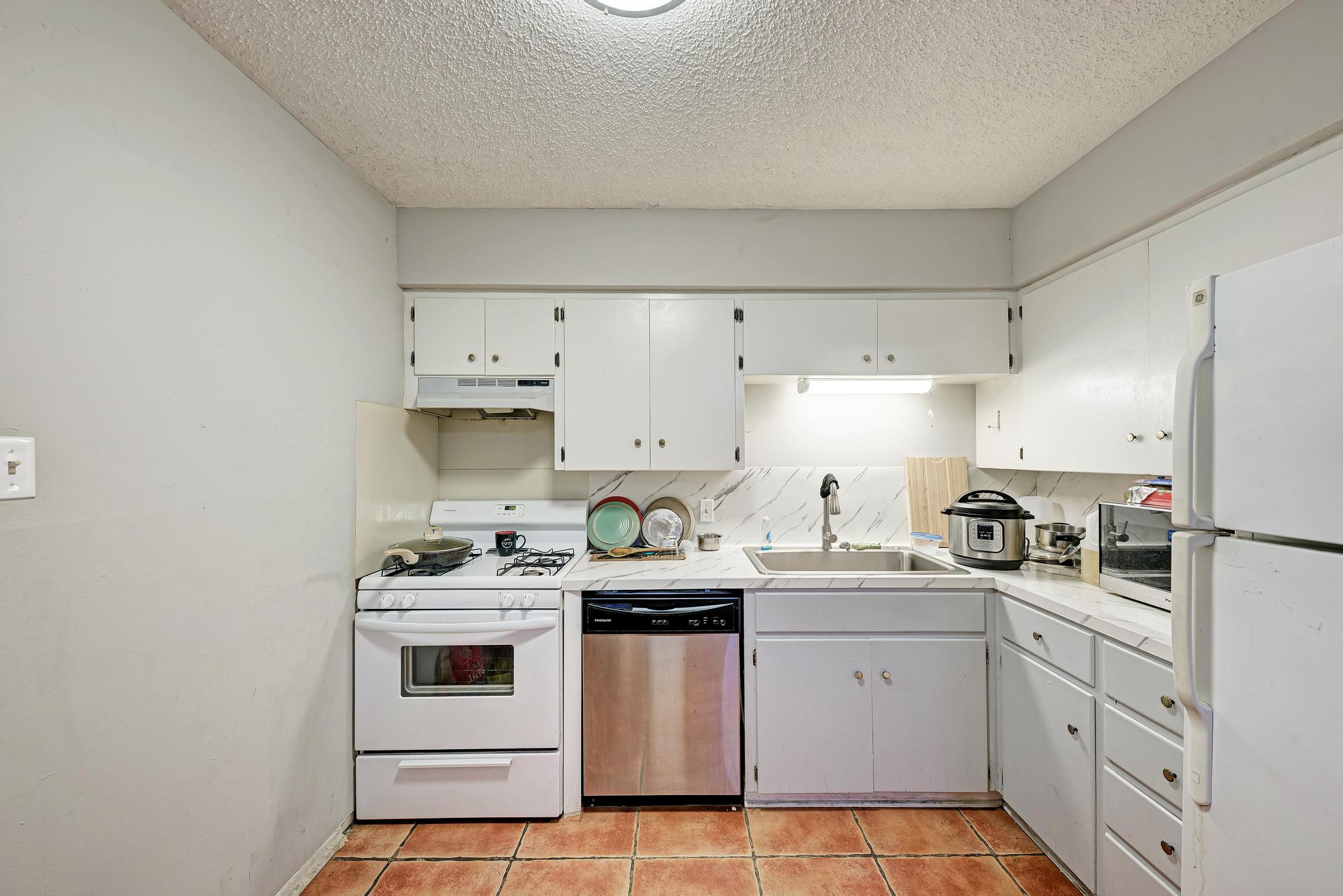 803 West 28th Street, Unit 102 Austin, TX 78705 - Photo 13 of 16 a kitchen with stainless steel appliances a white stove top oven and sink