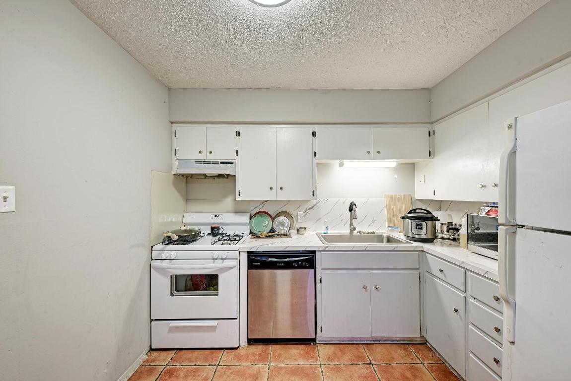 803 West 28th Street, Unit 102 Austin, TX 78705 - Photo 13 of 16 a kitchen with stainless steel appliances a stove a sink and white cabinets