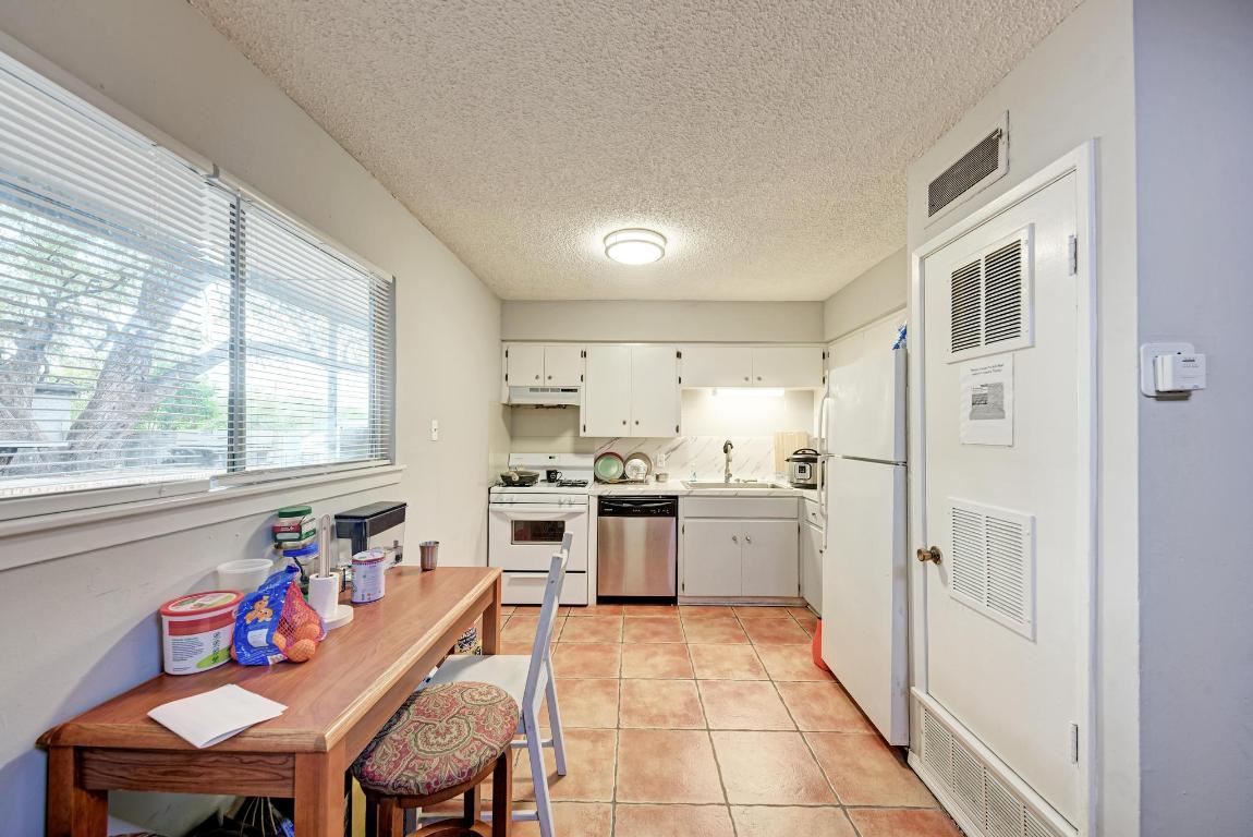 803 West 28th Street, Unit 102 Austin, TX 78705 - Photo 15 of 16 a kitchen with stainless steel appliances granite countertop a stove a sink dishwasher and a refrigerator with wooden floor