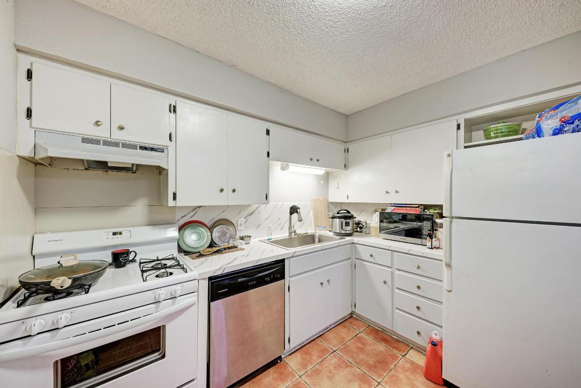 803 West 28th Street, Unit 102 Austin, TX 78705 - Photo 6 of 16 a kitchen with granite countertop a sink stove and refrigerator