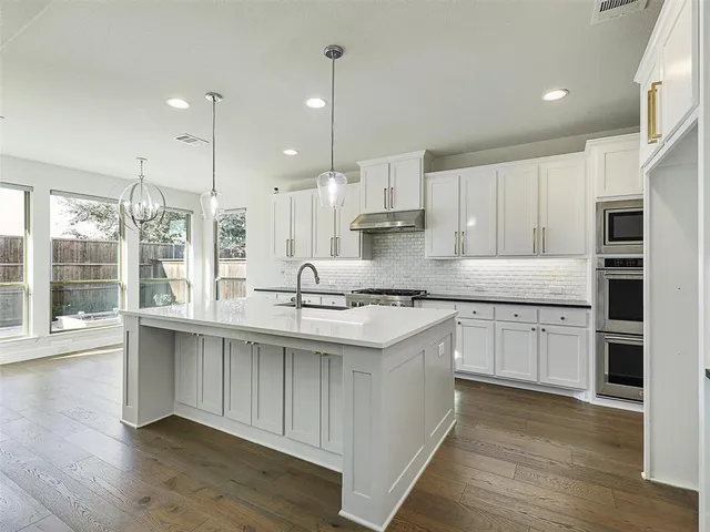 a kitchen with stainless steel appliances granite countertop a sink a stove and a wooden floors