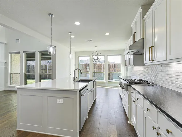a kitchen with a stove a sink a refrigerator and chairs
