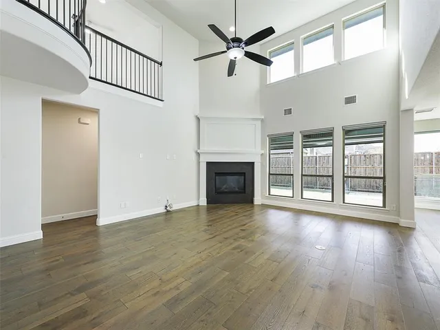 a view of an empty room with wooden floor fireplace and a window