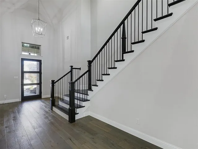 an entryway in a hallway with wooden floor and stairs