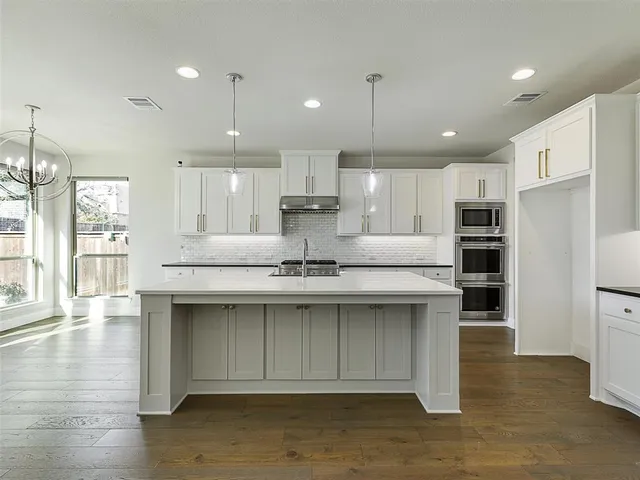 a kitchen with stainless steel appliances granite countertop a sink a stove and a wooden floors