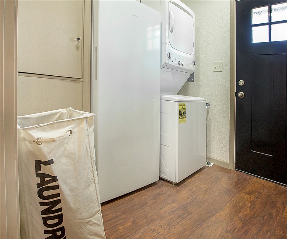 3726 St Joe Road Atkins, AR 72823 - Photo 31 of 41 Laundry area featuring wood-finish flooring, a white stacked washer and dryer, and a black exterior door with window panes