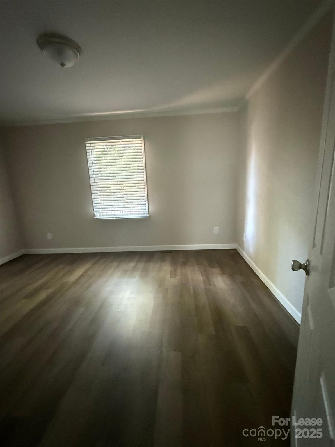 705 Oakshade Avenue Kannapolis, NC 28083 - Photo 7 of 21 an empty room with wooden floor and windows with curtains