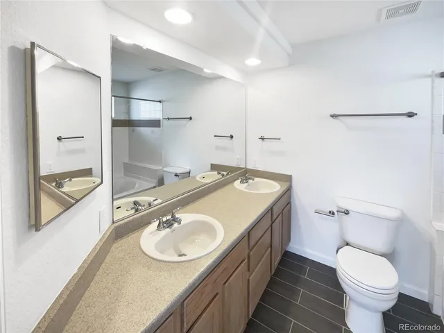 a bathroom with a granite countertop sink a toilet a mirror and shower