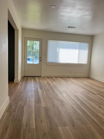 an empty room with wooden floor and windows