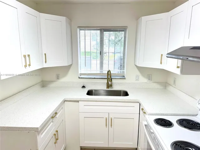 a kitchen with a sink a stove and white cabinets