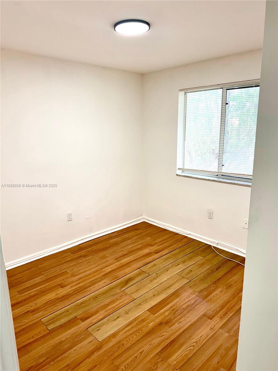 13942 Northeast 2nd Avenue, Unit 2B Miami, FL 33161 - Photo 7 of 10 a view of an empty room with wooden floor and a window