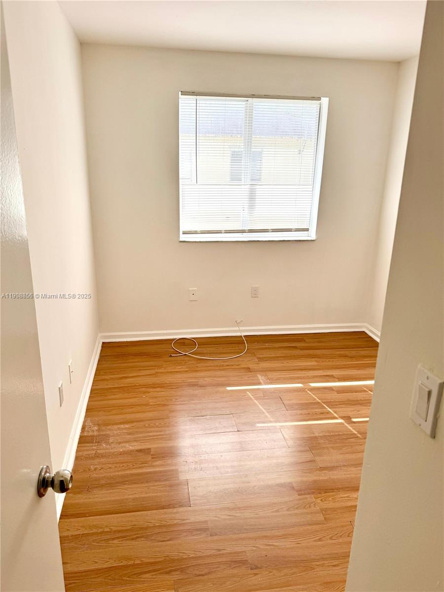 13942 Northeast 2nd Avenue, Unit 2B Miami, FL 33161 - Photo 8 of 10 a view of an empty room with wooden floor and a window