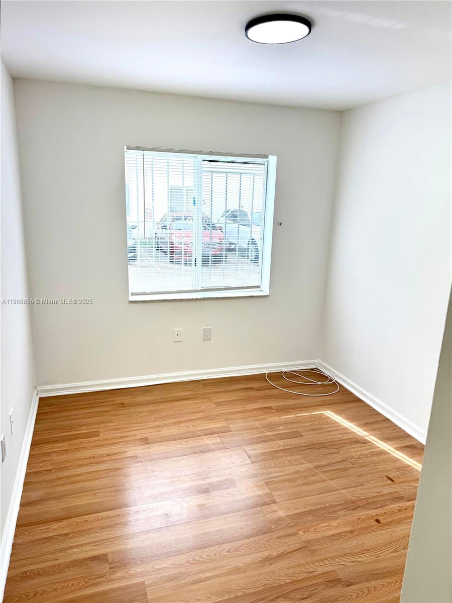 13942 Northeast 2nd Avenue, Unit 2B Miami, FL 33161 - Photo 10 of 10 an empty room with wooden floor and windows