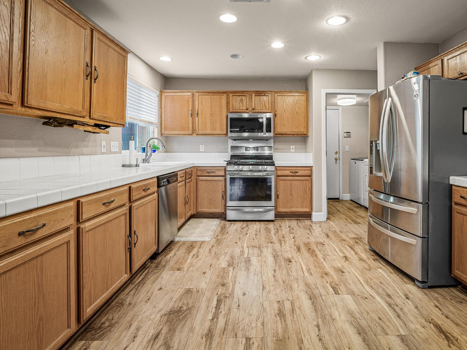 10893 Woolwich Way Mather, CA 95655 - Photo 6 of 24 a large kitchen with stainless steel appliances granite countertop a stove top oven a refrigerator with island and chairs with wooden floors