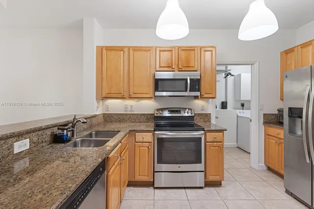 a kitchen with stainless steel appliances granite countertop a stove a sink and a refrigerator