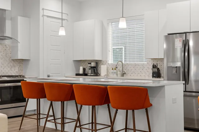 a kitchen with stainless steel appliances granite countertop a sink a stove a refrigerator and island with wooden floor