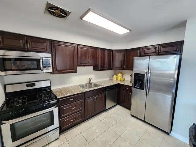 a kitchen with granite countertop a refrigerator and a stove top oven