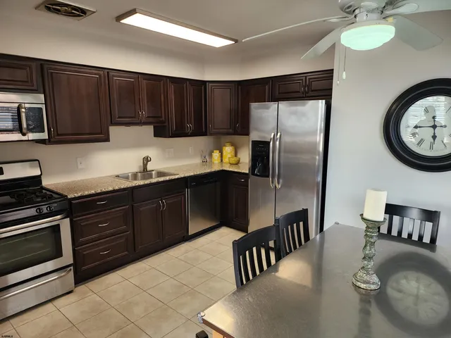 a kitchen with granite countertop a stove a refrigerator and a sink with wooden floor