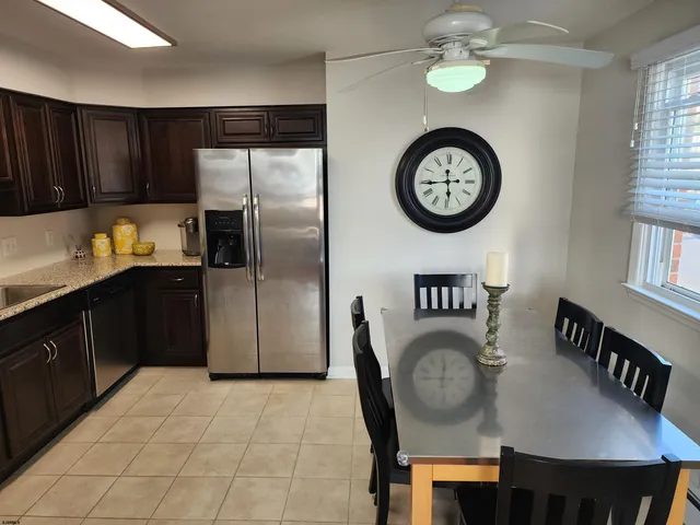 a kitchen with stainless steel appliances granite countertop a dining table a refrigerator and a clock on the table