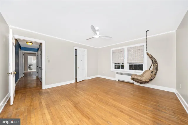 a view of empty room with wooden floor and fan