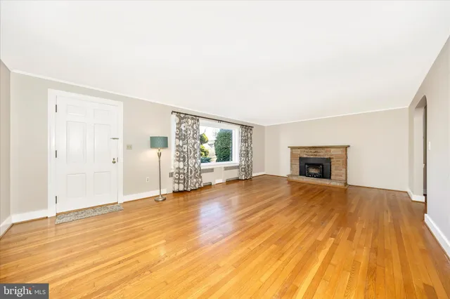 a view of empty room with wooden floor and fireplace
