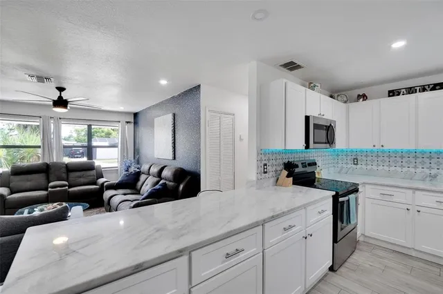 a living room with couches a dining table and chairs with kitchen view