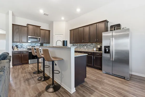 a kitchen with kitchen island granite countertop wooden floor stainless steel appliances and cabinets