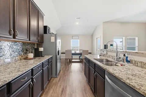 a kitchen with stainless steel appliances granite countertop a sink a stove and a wooden floors