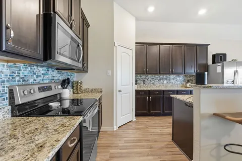 a kitchen with stainless steel appliances granite countertop a stove top oven a sink dishwasher and refrigerator