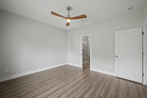 an empty room with wooden floor ceiling fan and windows